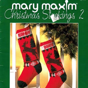 May include: A pair of red Christmas stockings with a knitted design featuring a reindeer, Christmas trees, and geometric patterns. The stockings have black heels and toes, and the text "RANCH" and "BARE" are visible on the cuffs. The image also includes the text "mary maxim Christmas Stockings 2".
