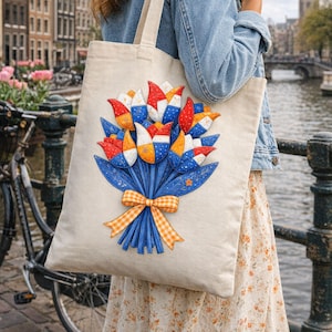 Op de afbeelding: Een beige draagtas met een boeket gestileerde tulpen in rood, wit, blauw en oranje. Het boeket is gebonden met een oranje geruite strik. De tas heeft lange handvatten.