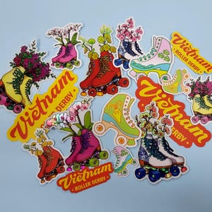 May include: A collection of colorful roller derby stickers featuring floral designs and the text "Vietnam Roller Derby".
