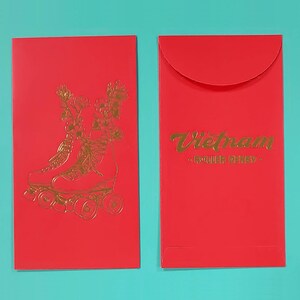 May include: Two red envelopes with gold foil designs. One envelope features a pair of roller skates with floral accents and the other envelope has the text "Vietnam Roller Derby" in gold foil.