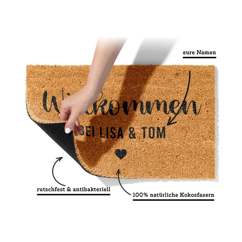 May include: A brown coir doormat with the text "Willkommen bei Lisa & Tom" and a heart symbol. The doormat is labeled as "rutschfest & antibakteriell" and "100% nat&uuml;rliche Kokosfasern".