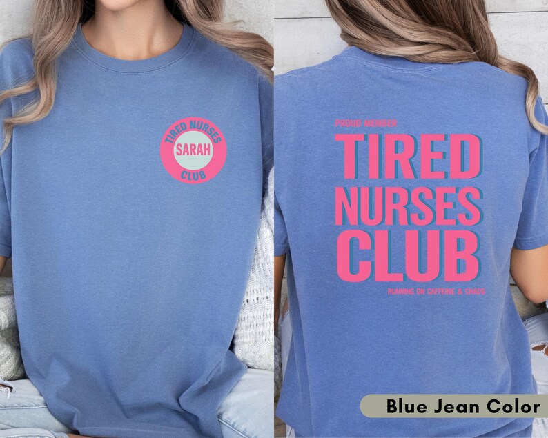 May include: Blue jean colored t-shirt with the text "TIRED NURSES CLUB" in pink on the back. The front of the shirt has a pink and white circular design that says "TIRED NURSES CLUB" and "SARAH".