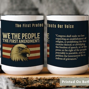 May include: White ceramic mug with a black handle and rim, featuring text and graphics related to the First Amendment. The design includes an eagle, the phrase "We the People," and the text of the First Amendment. The mug is printed on both sides.