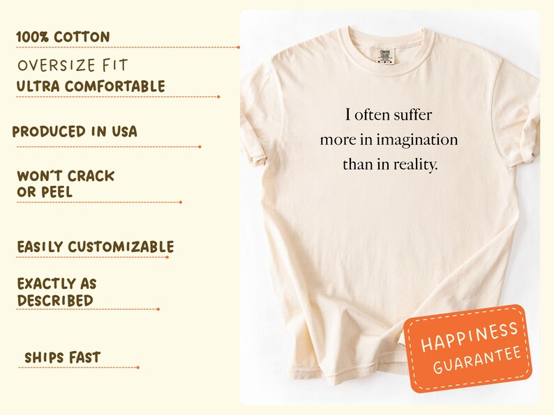 May include: Cream-colored t-shirt with the quote "I often suffer more in imagination than in reality." The shirt has an oversized fit and is made of 100% cotton. A small orange tag with the words "Happiness Guarantee" is attached.