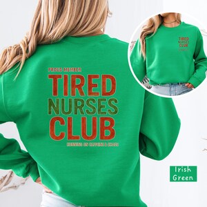 May include: A green sweatshirt with the text "TIRED NURSES CLUB" in red and green lettering. The phrase "RUNNING ON CAFFEINE & CHAOS" is below the club name. A smaller image of the sweatshirt is in the upper right corner.