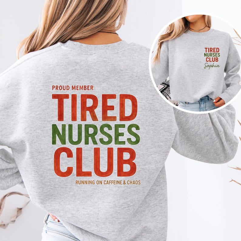 May include: A light gray sweatshirt with the text "PROUD MEMBER TIRED NURSES CLUB" in red and green lettering. The phrase "RUNNING ON CAFFEINE & CHAOS" is printed below. A smaller version of the logo is on the front, with the name "Sophia" below.