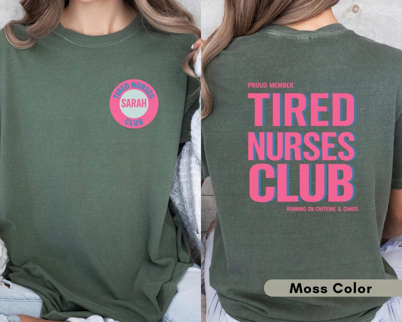 May include: Moss green t-shirt with the text "TIRED NURSES CLUB" in pink and blue on the back. The front features a circular design with "TIRED NURSES CLUB" and the name "SARAH". The shirt is a comfortable fit.
