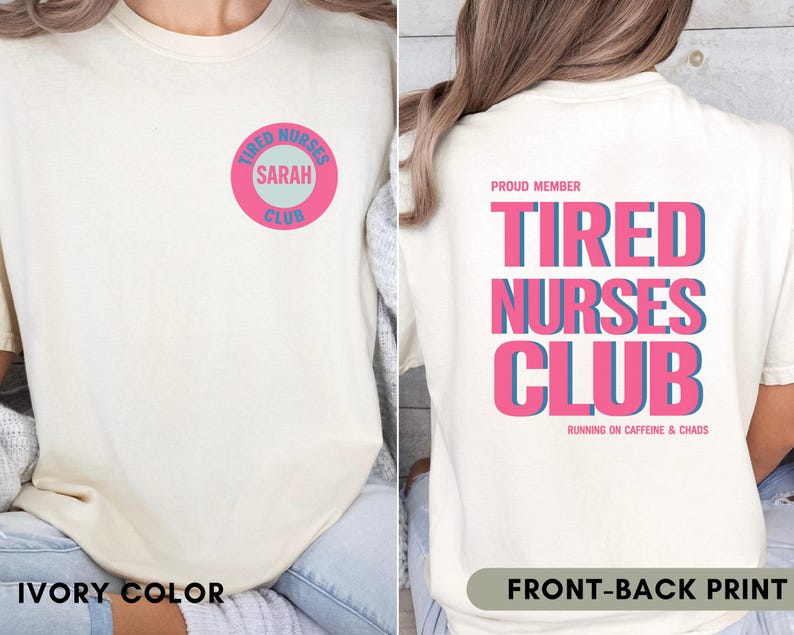 May include: Ivory-colored t-shirt with a front and back print. The front features a pink and blue circular design with the text "Tired Nurses Club" and "Sarah". The back displays "Tired Nurses Club" in pink and blue, with "Running on Caffeine & Chaos".
