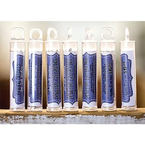 May include: A collection of clear plastic tubes with white and blue labels. The labels read "Primitive Gatherings" and "Binding Needles". Each tube has a loop at the top.