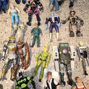 May include: A collection of colorful action figures, including a knight, Batman, and a robot. The figures are in various poses and feature detailed designs. The toys are made of plastic and are in good condition.