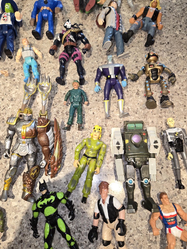 May include: A collection of colorful action figures, including a knight, Batman, and a robot. The figures are in various poses and feature detailed designs. The toys are made of plastic and are in good condition.