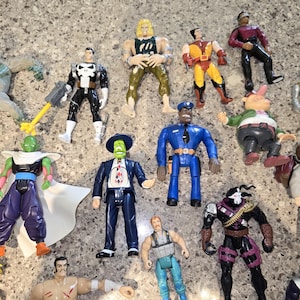 May include: A collection of action figures featuring various characters. The figures are in different poses and outfits, with a variety of colors and designs. Some figures have weapons or accessories.