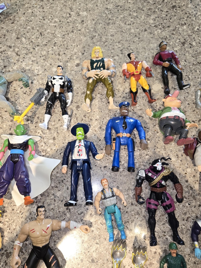 May include: A collection of action figures featuring various characters. The figures are in different poses and outfits, with a variety of colors and designs. Some figures have weapons or accessories.