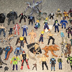 May include: A collection of various action figures, including superheroes, monsters, and other characters. The figures are in various colors and poses, made of plastic, and are of different sizes.