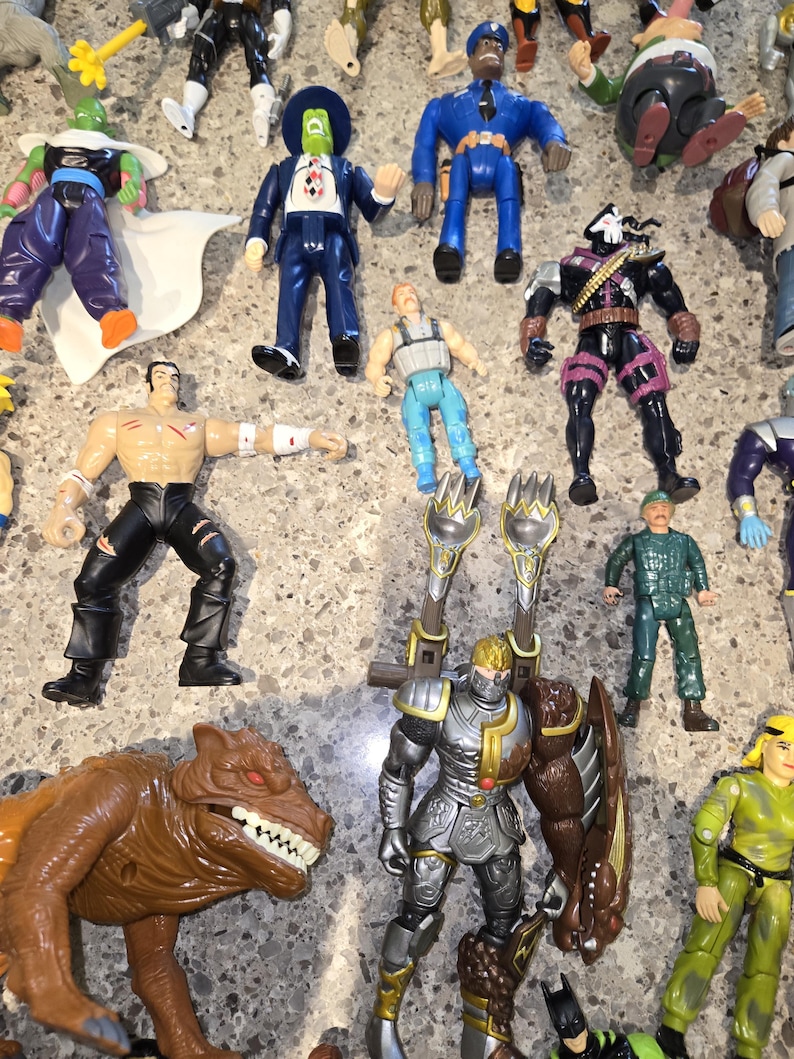 May include: A collection of colorful action figures, including a blue police officer, a masked figure in a suit, a knight in silver armor, and a brown dinosaur-like creature. Various other characters are also visible.
