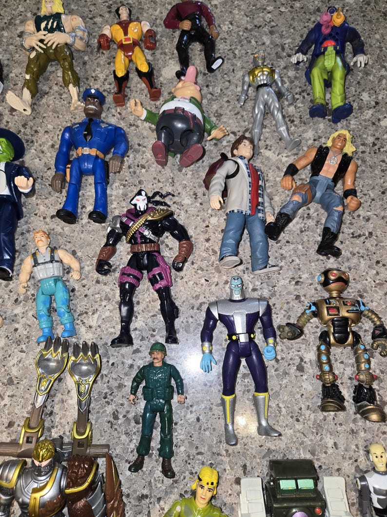 May include: A collection of vintage action figures, featuring various characters in vibrant colors. The figures include superheroes, robots, and other fantasy characters. Some figures are in shades of blue, green, yellow, and black.