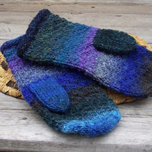 Puede incluir: Un par de guantes tejidos de color azul, morado y verde con un patrón texturizado. Los guantes están sobre una cesta tejida.