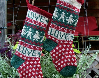 May include: Two knitted Christmas stockings with red, green, and white patterns. The stockings are hanging on a wire fence. The word "LOVE" is knitted into the design. The stockings have green heels and toes.