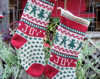 May include: Two white and red Christmas stockings with green and white patterns. The stockings have the word "JOY" embroidered on them.