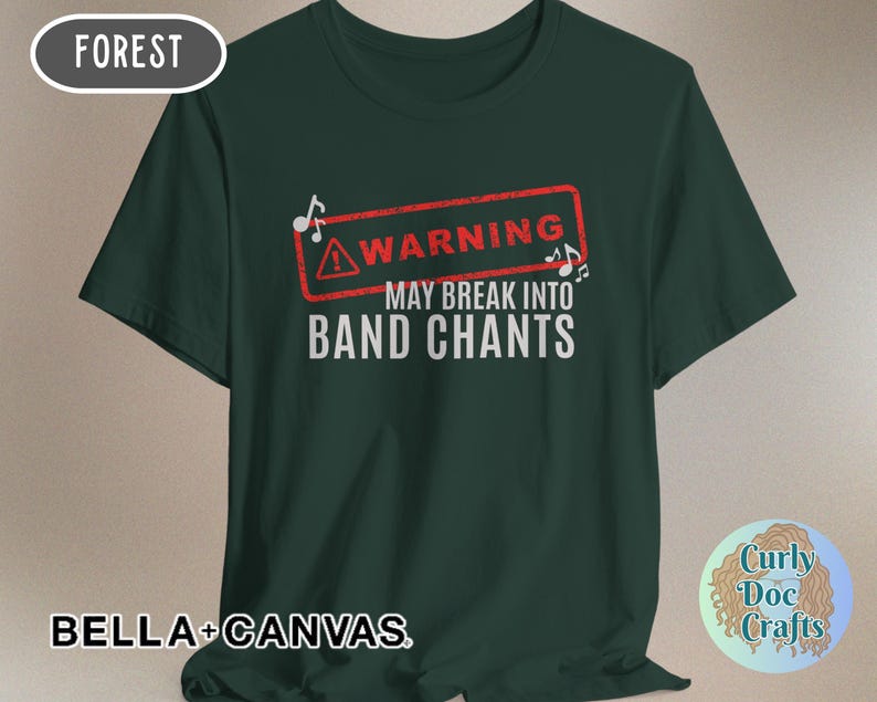 May include: Forest green t-shirt with the text "WARNING MAY BREAK INTO BAND CHANTS" in white. The word "WARNING" is inside a red rectangle with musical notes. The shirt is made of Bella+Canvas material.