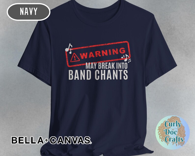 May include: Navy blue t-shirt with the text "WARNING MAY BREAK INTO BAND CHANTS" in white. The warning is in a red rectangle with musical notes. The shirt is made of Bella+Canvas material.