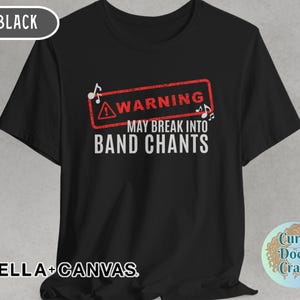 May include: Black t-shirt with the text "WARNING MAY BREAK INTO BAND CHANTS" in white, inside a red warning sign. The shirt also has the text "BELLA + CANVAS" at the bottom.