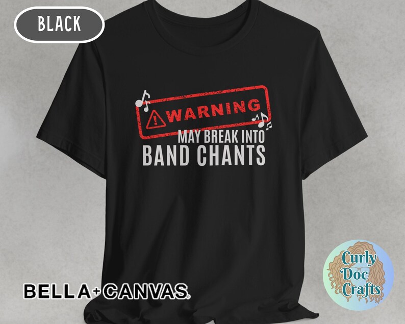 May include: Black t-shirt with the text "WARNING MAY BREAK INTO BAND CHANTS" in white, inside a red warning sign. The shirt also has the text "BELLA + CANVAS" at the bottom.