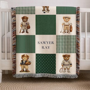 May include: A personalized baby blanket with a patchwork design featuring teddy bears dressed in sports attire. The blanket has green and white checkered, striped, and dotted patterns. The name "SAWYER RAY" is displayed in the center.
