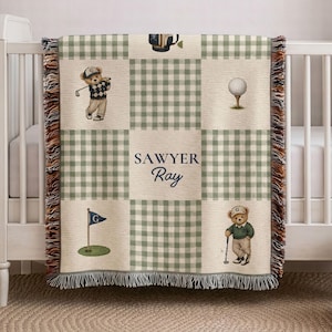 May include: A woven throw blanket featuring a green and white gingham pattern with alternating squares displaying illustrations of teddy bears playing golf, a golf ball on a tee, and a golf flag. The center square reads Sawyer Ray.