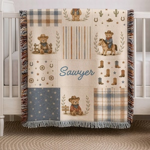 May include: A woven throw blanket featuring a patchwork design with teddy bears in cowboy hats, horses, cacti, horseshoes, and boots. The center panel displays the name Sawyer in blue script. The blanket has a fringed edge and plaid patterns.