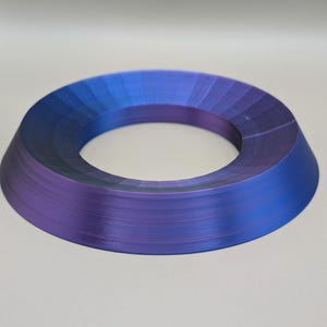 May include: A ring-shaped, 3D printed object with a gradient of blue and purple colors. The object is smooth and has a glossy finish.