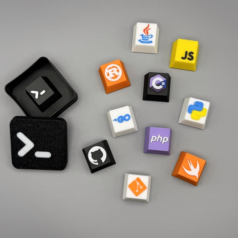 Puede incluir: Un conjunto de teclas personalizadas y coloridas con logotipos de varios lenguajes de programaci&oacute;n, como Java, JavaScript, Python y C++. Las teclas son de varios colores, como blanco, amarillo, naranja y morado. Tambi&eacute;n hay dos teclas negras con s&iacute;mbolos blancos.
