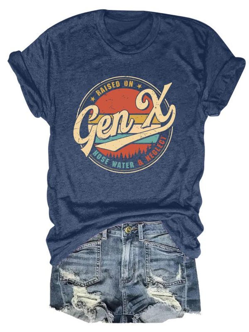Puede incluir: Camiseta azul marino con un dise&ntilde;o retro que dice "Raised on Gen X, Hose Water & Neglect" en un dise&ntilde;o circular con acentos naranja, amarillo y turquesa. La camiseta se combina con pantalones cortos de mezclilla.