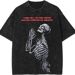 Puede incluir: Camiseta negra con un aspecto desgastado que presenta un gr&aacute;fico de esqueleto blanco y el texto "COME HELL OR HIGH WATER WOLVES FOREVER NO WEAPON" en rojo.