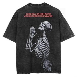Puede incluir: Camiseta negra con un aspecto desgastado que presenta un gr&aacute;fico de esqueleto blanco y el texto "COME HELL OR HIGH WATER WOLVES FOREVER NO WEAPON" en rojo.