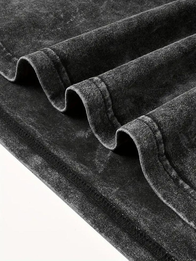 K&ouml;nnte beinhalten: Nahaufnahme der schwarzen Stoffkante eines Kleidungsst&uuml;cks, die die N&auml;hdetails zeigt. Der Stoff hat einen abgenutzten, Vintage-Look.