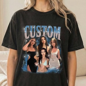 Puede incluir: Una camiseta negra de manga corta con la palabra CUSTOM en letras grandes azules y blancas en la parte superior. Debajo del texto, un gráfico muestra a tres personas posando, rodeadas por un efecto de rayo azul sobre un fondo oscuro.