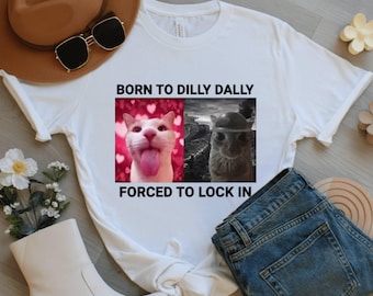 May include: White t-shirt with the text "BORN TO DILLY DALLY FORCED TO LOCK IN". The shirt features two images: a cat with its tongue out and a llama. The cat image has a pink heart background.