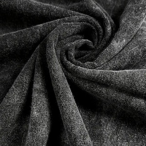 K&ouml;nnte beinhalten: Nahaufnahme eines dunkelgrauen Stoffes mit strukturierter Oberfl&auml;che. Der Stoff ist gefaltet und drapiert und erzeugt einen weichen und einladenden Look.