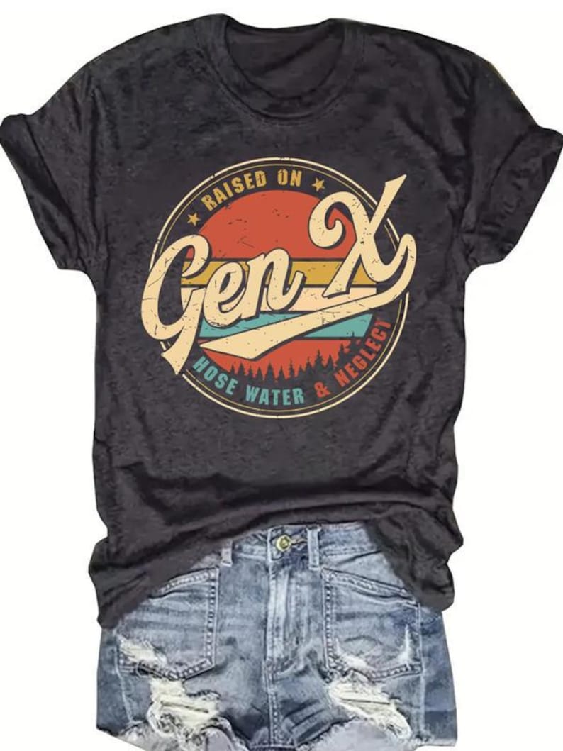 Puede incluir: Camiseta gris oscuro con un dise&ntilde;o gr&aacute;fico circular retro que dice "Raised on Gen X Hose Water & Neglect". La camiseta se combina con pantalones cortos de mezclilla.