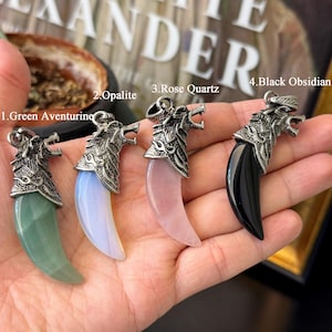 Può includere: Quattro ciondoli con pietre preziose. Ogni ciondolo presenta una testa di lupo color argento e una pietra curva e lucidata. Le pietre sono avventurina verde, opalite, quarzo rosa e ossidiana nera. Tenuti in una mano.