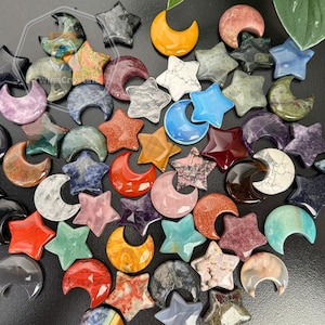 Peut inclure: Une collection de sculptures de pierres précieuses en forme d'étoiles et de croissants de lune. Les sculptures sont de différentes couleurs, dont le bleu, le rouge, le vert et le blanc. Les pierres précieuses ont une finition polie et sont disposées sur une surface sombre.