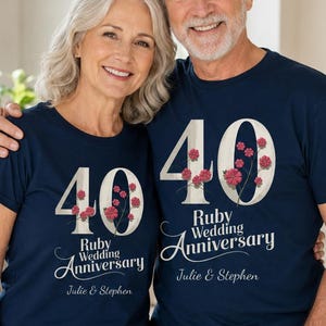 Könnte beinhalten: Zwei marineblaue T-Shirts mit kurzen Ärmeln, die eine große weiße Zahl 40 mit roten Blumenakzenten zeigen. Unter der Zahl steht der Text Ruby Wedding Anniversary und die Namen Julie & Stephen in weißer Schreibschrift auf der Vorderseite.
