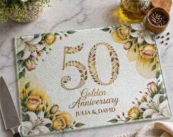May include: Rectangular glass cutting board with a floral design and the text "50 Golden Anniversary Julia & David". The design features gold-colored numbers and text, with yellow roses and white lilies. A knife is on the left.