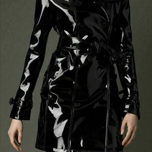 May include: A black patent leather trench coat with a double-breasted closure, a belt, and a collar.