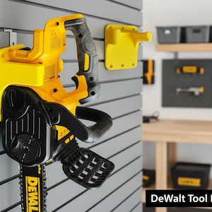 Könnte beinhalten: Eine gelb-schwarze DeWalt-Kettensäge an einer grauen Lamellenwand. Die Kettensäge wird von einem gelben Werkzeughalter gehalten. Zusätzliche gelbe Werkzeughalter sind an der Wand zu sehen. Der Text "DeWalt Tool Holder" befindet sich unten.