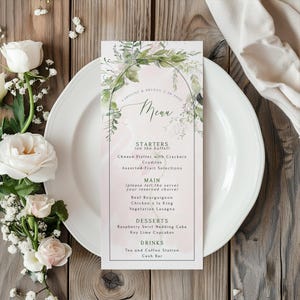 May include: A wedding menu card with a floral design, featuring the names "Caroline & Bryson" and the date "7-28-2026". The menu lists starters, main courses, desserts, and drinks. The card is on a white plate, with flowers and a wooden background.