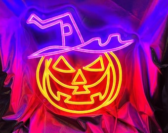May include: A neon sign shaped like a pumpkin with a witch's hat. The pumpkin is orange and the hat is purple. The sign is lit up and glowing.