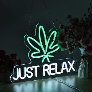 Puede incluir: Letrero de neón con una hoja de marihuana verde y las palabras "JUST RELAX" en blanco.