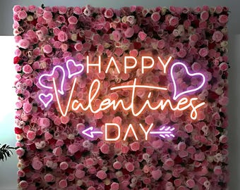 May include: A wall of pink and red roses forms the backdrop for a neon sign that reads "HAPPY Valentines DAY." The sign features heart shapes and an arrow. The overall theme is romance and celebration.